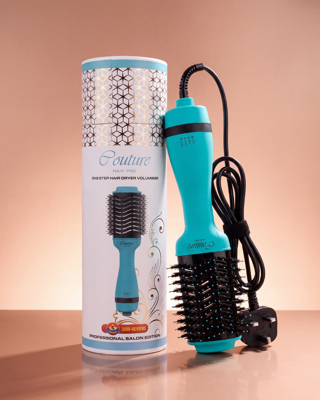 A turquoise and black round hair dryer brush shown next to its white branded packaging cylinder on a warm peach studio background.